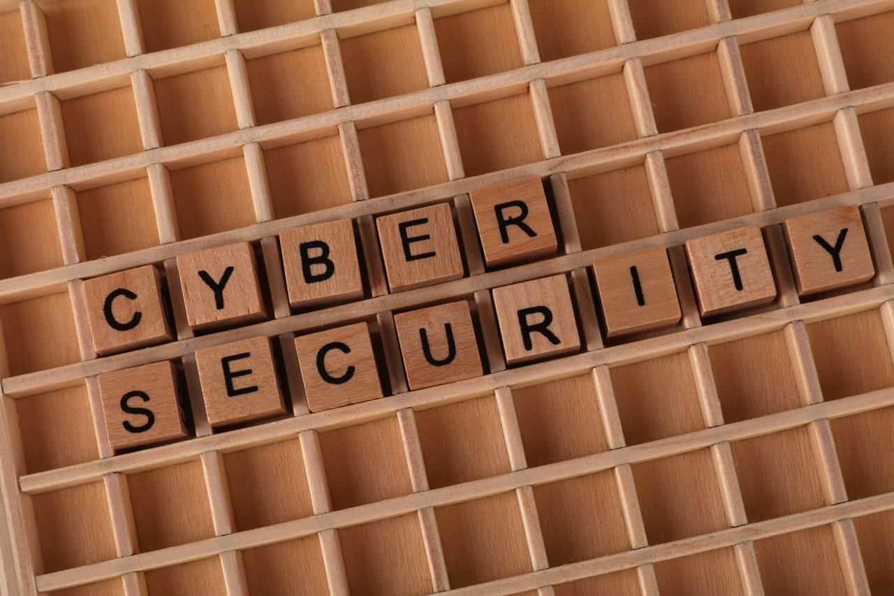 Wooden blocks spelling Cyber Security on a wooden grid background.